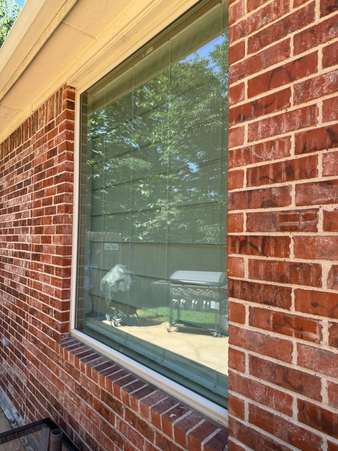 Clean picture window on red brick overlooking the back patio