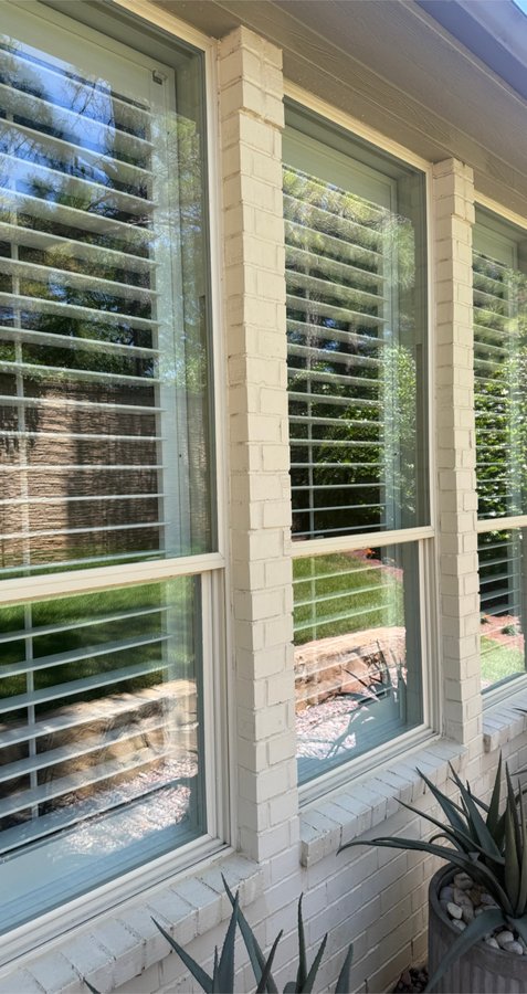Row of louvered windows on a white brick home