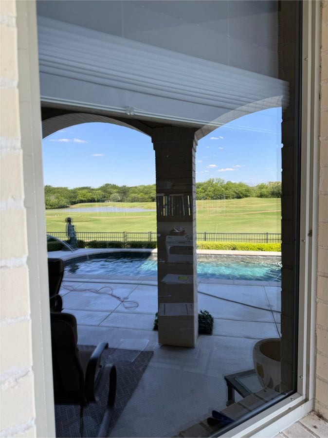 Looking through a clean window out to a pool and golf course